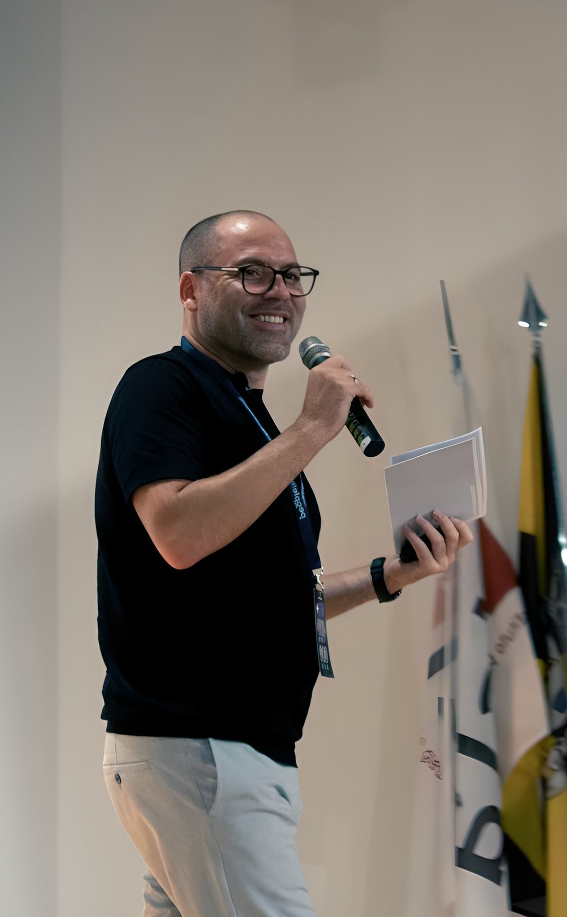 André Bacêlo e Costa com microfone em palco no PeopleEmpreende 2024, durante a sessão «Inteligência Artificial na Prática»