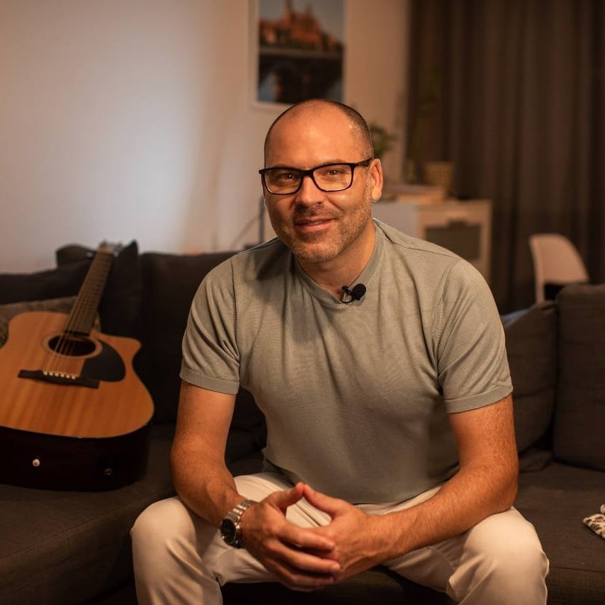 André Bacêlo e Costa sentado num sofá, com uma guitarra ao lado