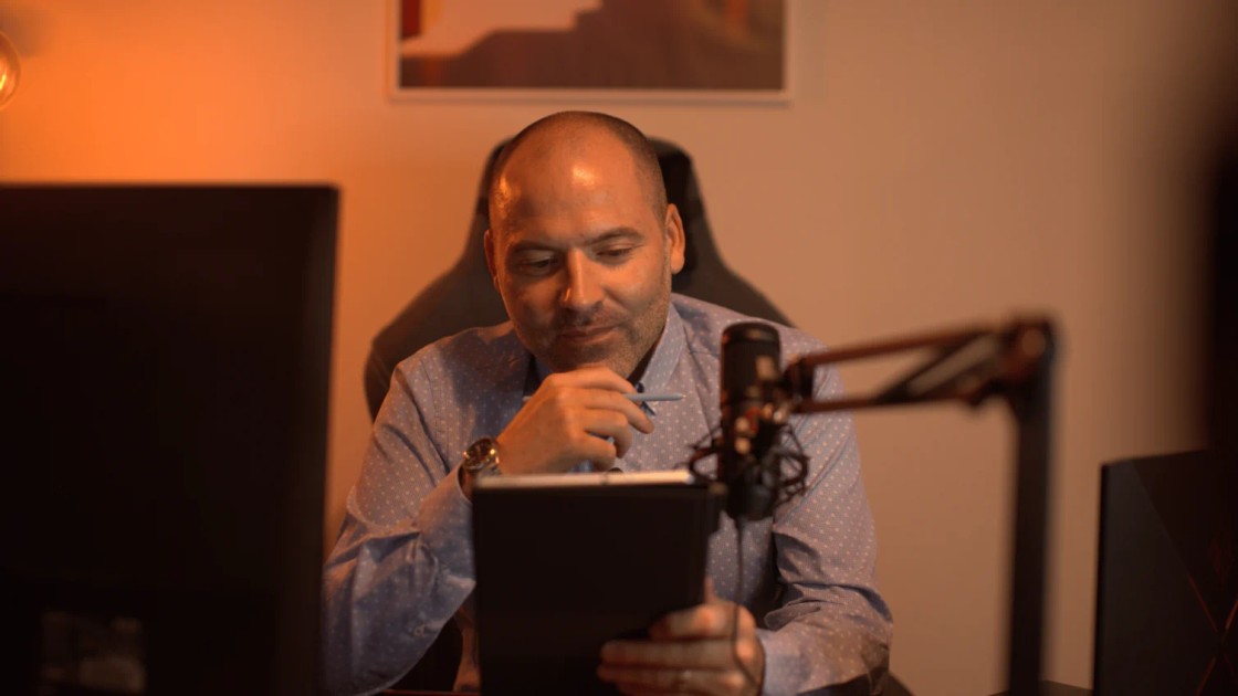 André Bacêlo e Costa sentado à secretária, a ler num tablet com uma caneta na mão, num gabinete com luz quente